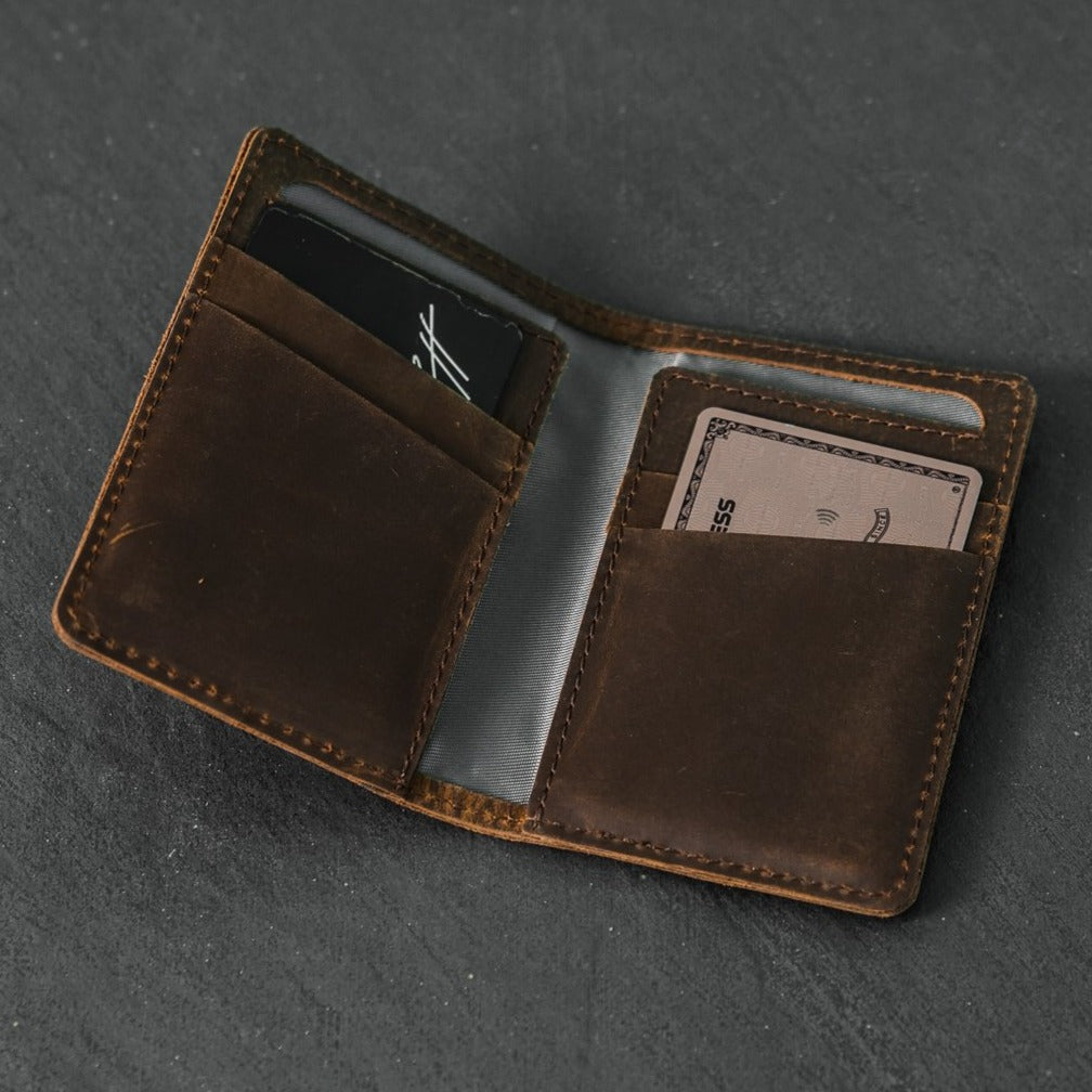 Brown leather messenger wallet open with two inner card pockets; one card shows ESS and a contactless symbol.
