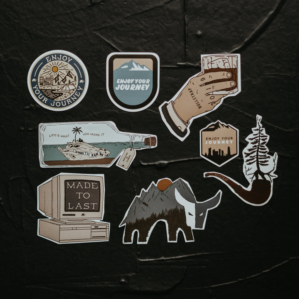 A collection of stickers featuring designs like mountains, a bottle, and a hand holding a drink, with text 'Enjoy Your Journey' and 'Made to Last'.