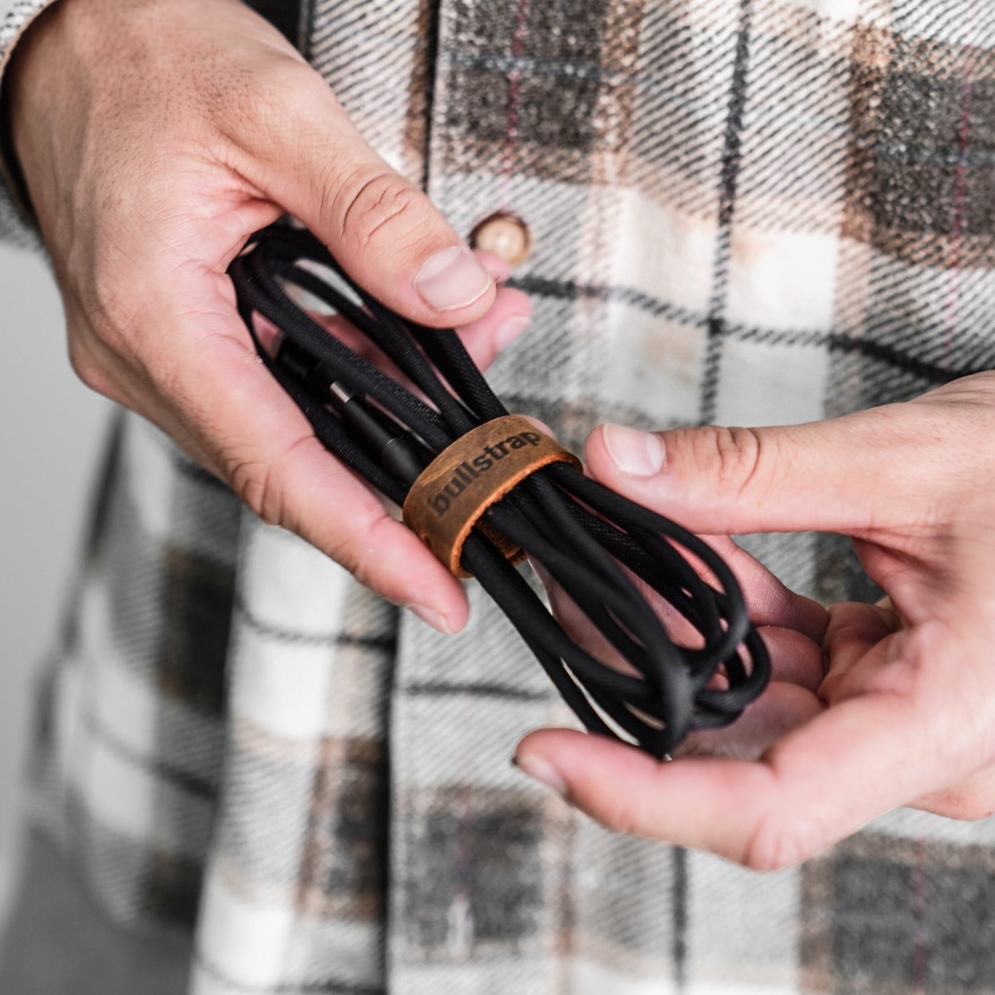 A person holding a charging cable with a leather management loop.