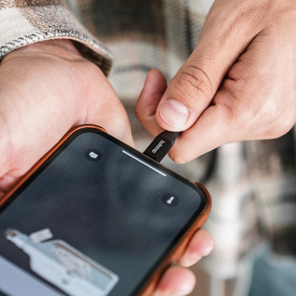 Hand inserting bullstrap charging cable into smartphone charging port