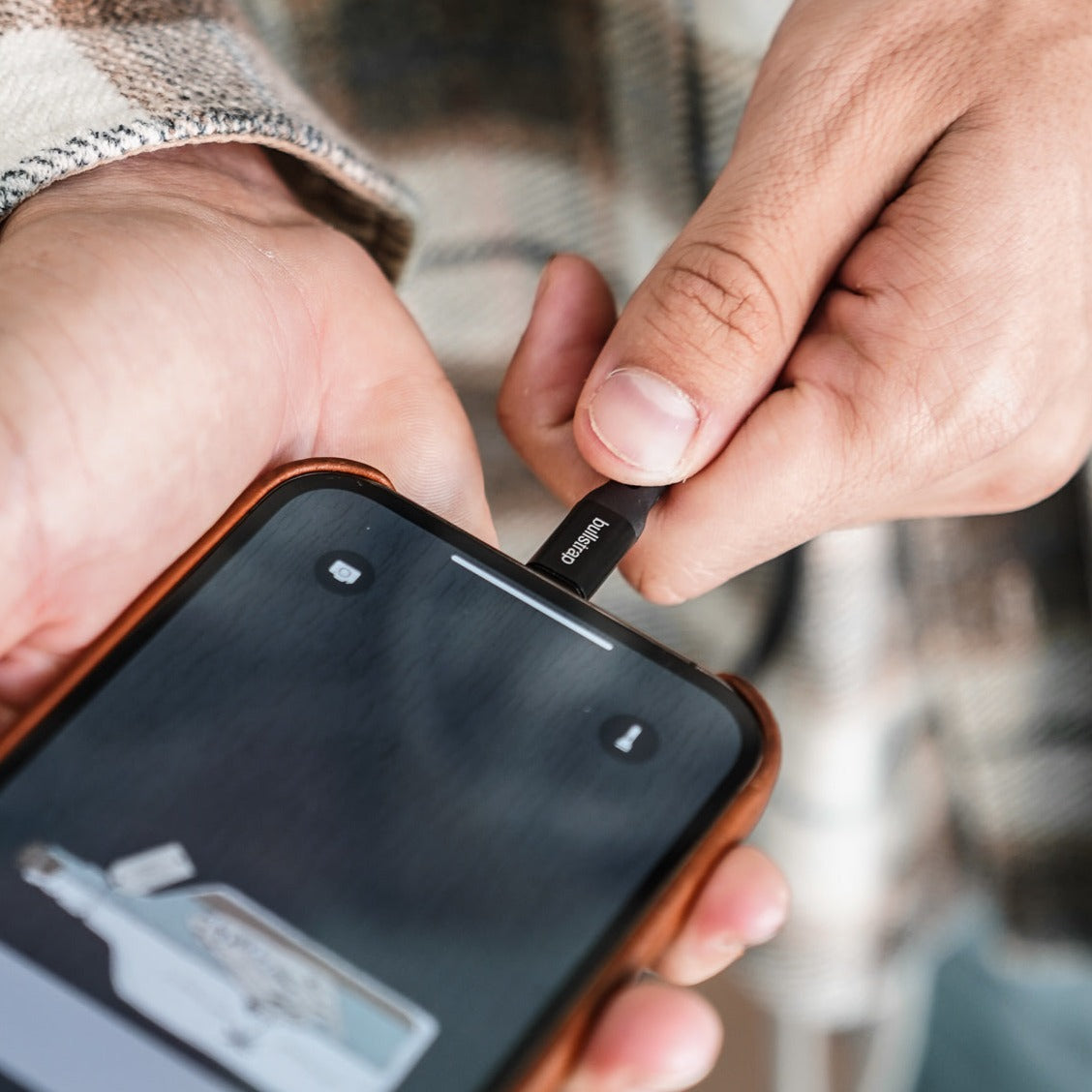 Hand inserting bullstrap charging cable into smartphone charging port