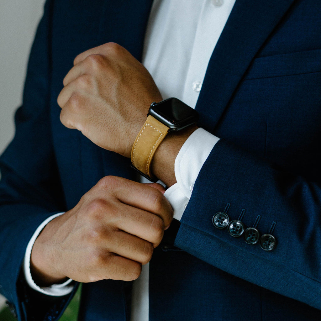 A person wearing a leather Apple Watch strap in a formal setting, showcasing the strap's design and color.