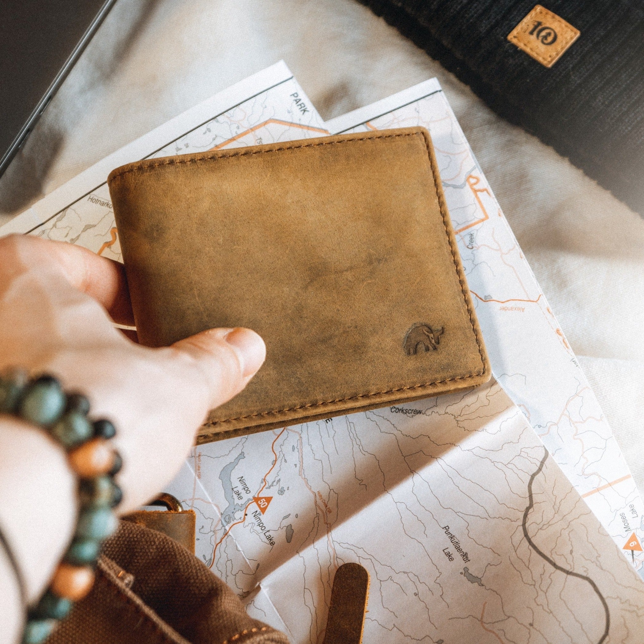 Hand holding brown leather wallet with embossed bull on folded map.