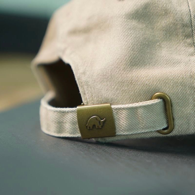 Tan canvas dad hat back strap with brass buckle showing small elephant logo