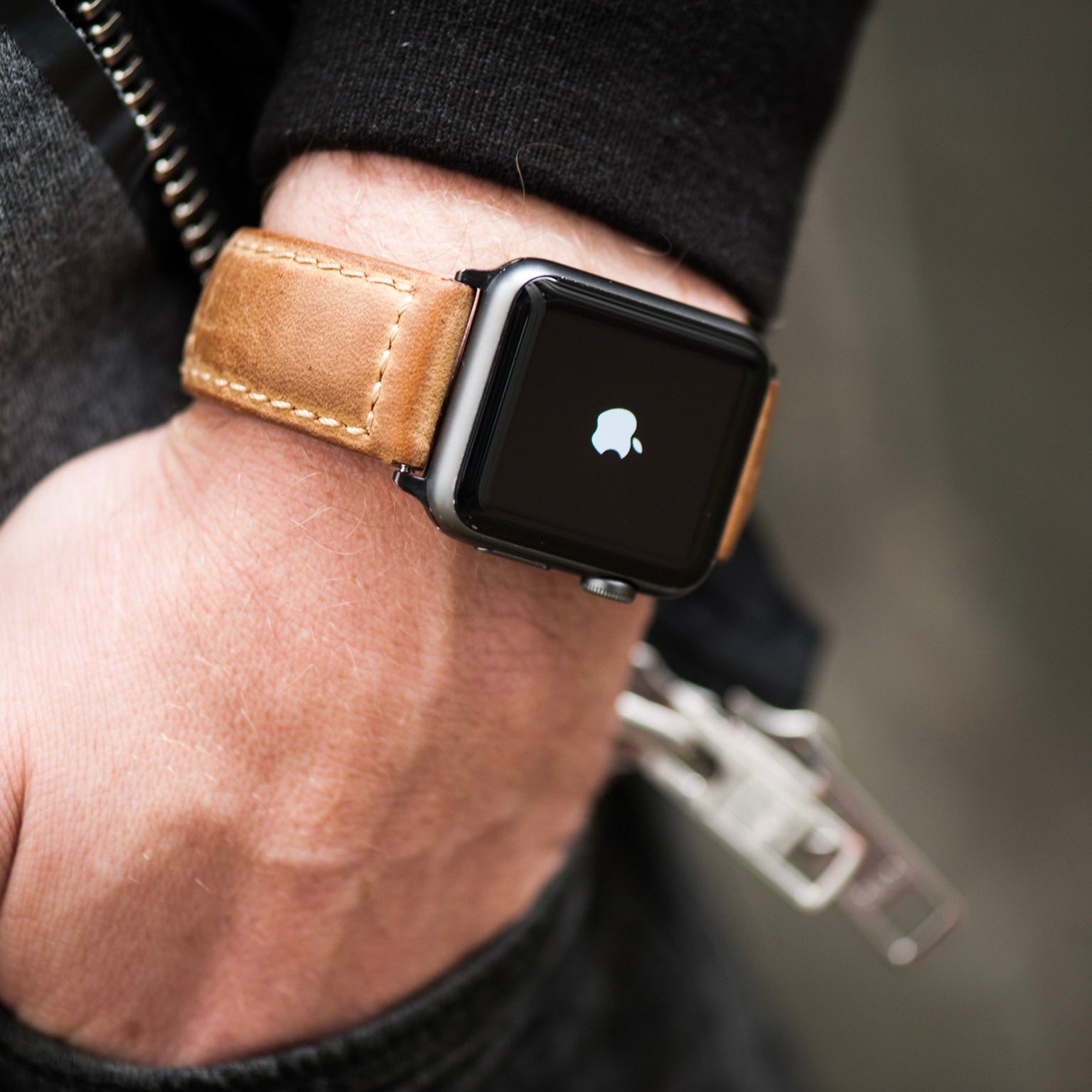 A person wearing a leather Apple Watch strap on their wrist, showcasing the strap's design and color.