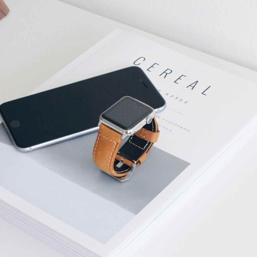 Brown leather Apple Watch strap on a magazine and smartphone
