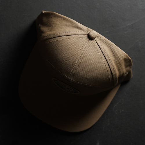 Top view of the EYJ Badge Hat in tan color, showcasing its design and fabric texture.