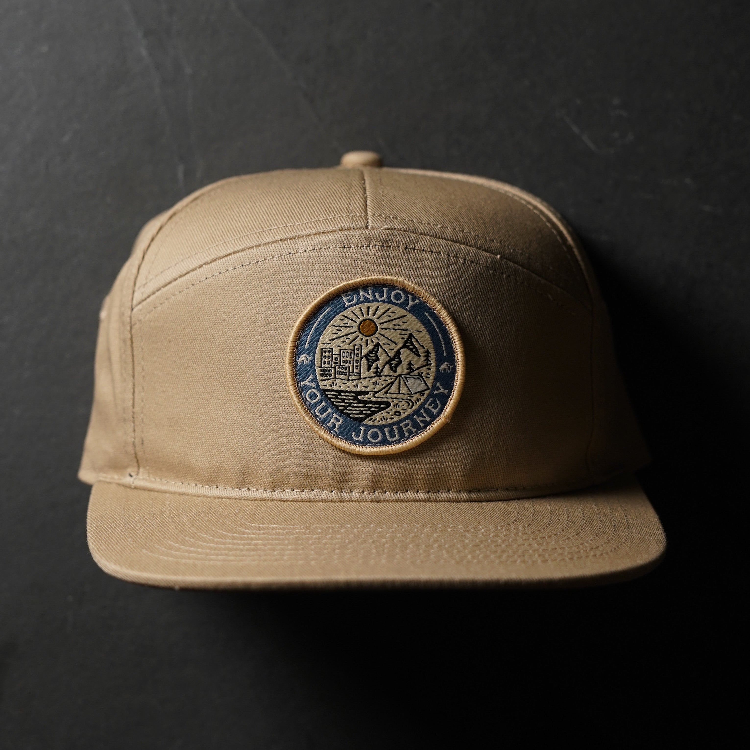 A tan hat with a circular badge that says 'ENJOY YOUR JOURNEY'