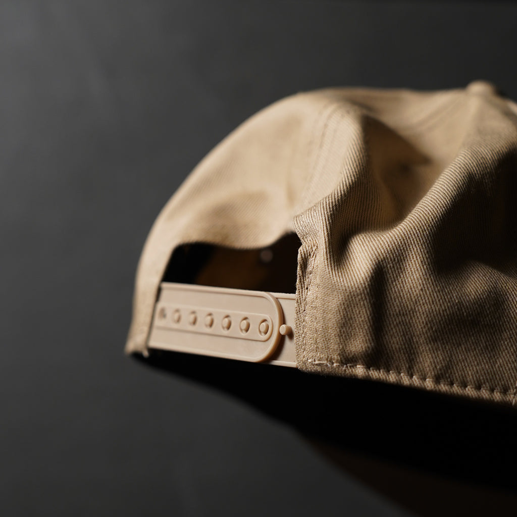 Close-up of the back of the EYJ Badge Hat in tan color, showing the snap-back adjustment.