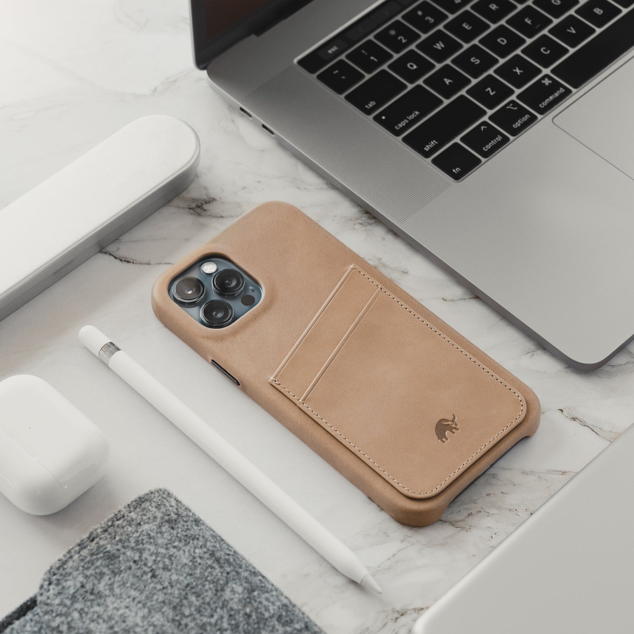 Minimalist Portfolio Case in Dune color, featuring card slot, placed on a marble surface with tech accessories.