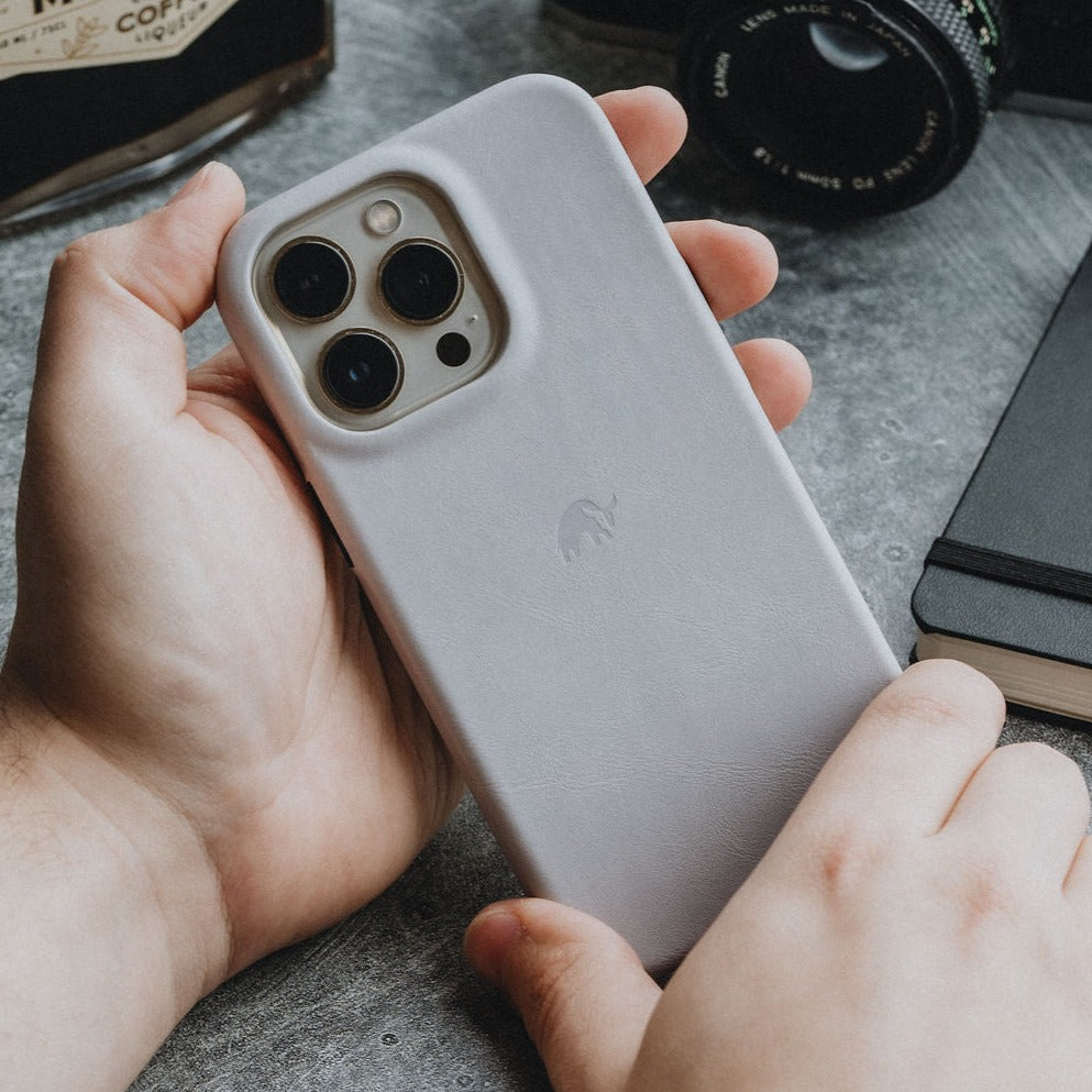 A person holding a minimalist iPhone case in light gray with a logo on the back.