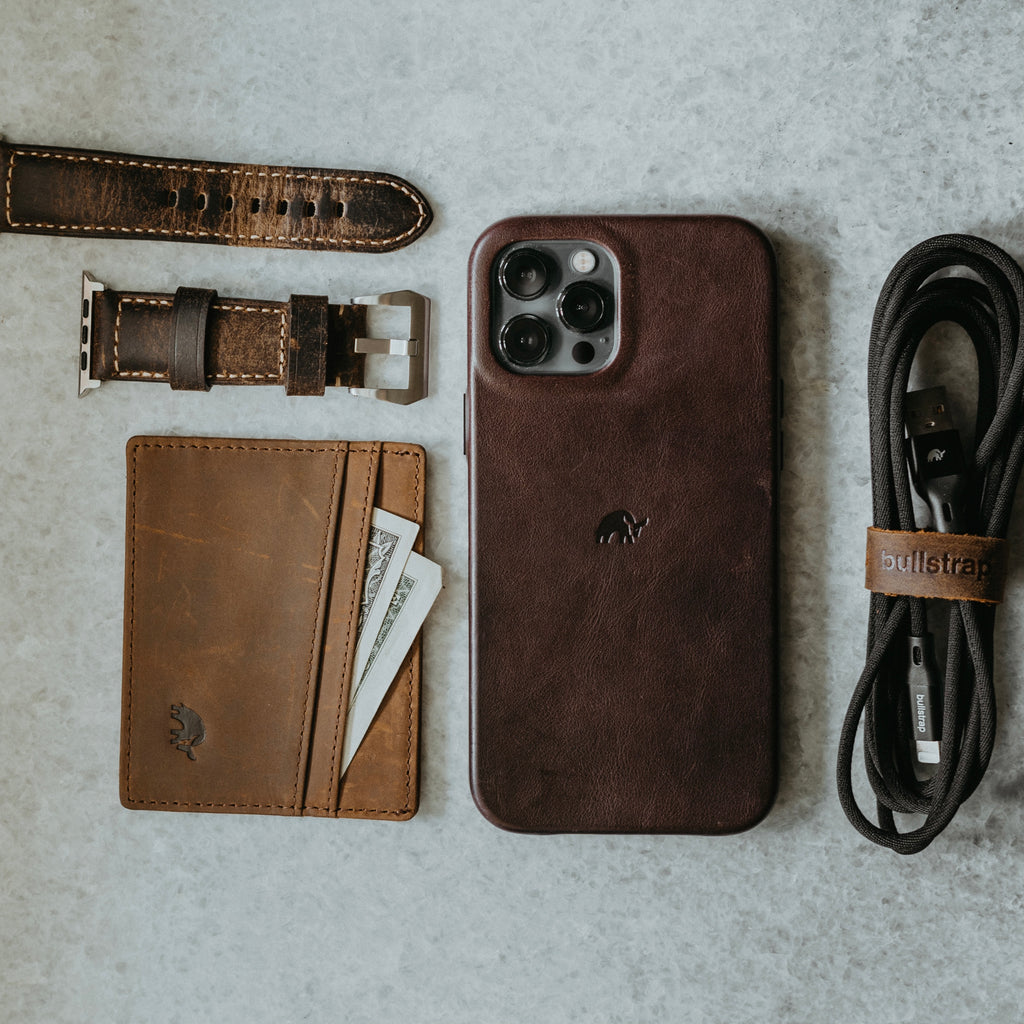 Leather Card Holder Terra with cash, matching leather iPhone case, watch strap, and cable labeled bullstrap.