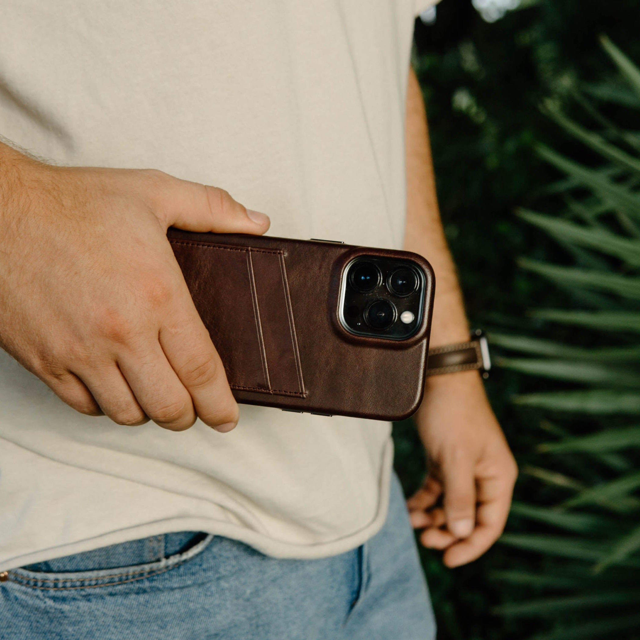 A person holding a brown leather iPhone case with card slots.